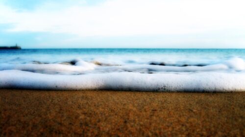 Serene Ocean Foam Washing Over Sandy Beach Desktop Wallpaper