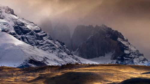 Stunning Snowy Mountain Peaks under Dramatic Cloudy Skies 4K Wallpaper