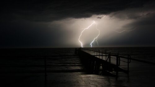 Dramatic Night Lightning Strike Over Ocean Pier 4K Wallpaper