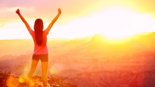Woman Celebrating Success at Sunset Over Canyon Peak Desktop Wallpaper