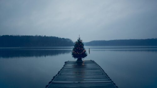 Lonely Christmas Tree on Wooden Pier Over Calm Lake 4K Wallpaper
