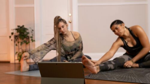 Women Stretching Yoga on Mats Before Tablet 4K Desktop Wallpaper