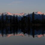 Snow-Capped Mountains Reflected in Still Water at Sunset