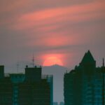Spectacular Sunset Behind Distant Mountains Over City Buildings