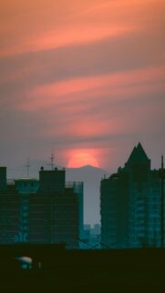 Spectacular Sunset Behind Distant Mountains Over City Buildings