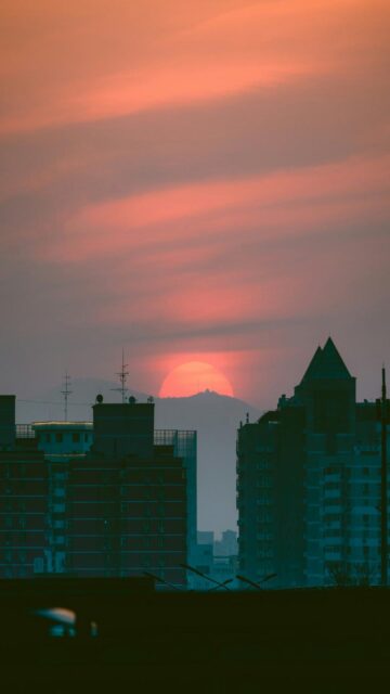 Spectacular Sunset Behind Distant Mountains Over City Buildings