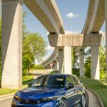 Urban Oasis: Blue Sedan Under Concrete Overpass