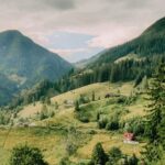 Serene Nature Scene: Lush Green Valley Surrounded by Mountains under Cloudy Sky