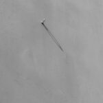 Shadowy Focus: A Single Nail on a Wall