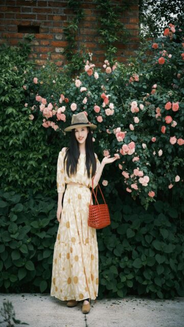 Woman in a Hat and Dress Stands by Roses