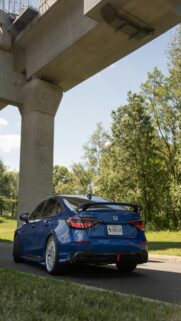 Urban Oasis – Blue Sports Sedan Parked Under A Concrete Overpass
