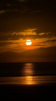Golden Sunset Over Calm Ocean And Distant Mountains