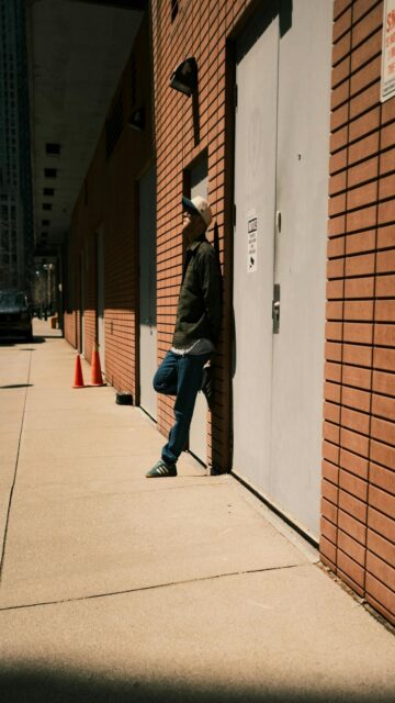Urban Oasis - Man Leaning Against Brick Building