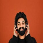 Man With Headphones Smiles Against Orange Background
