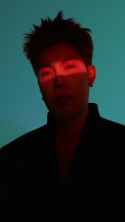Man with Red Light Across Face on Teal Background