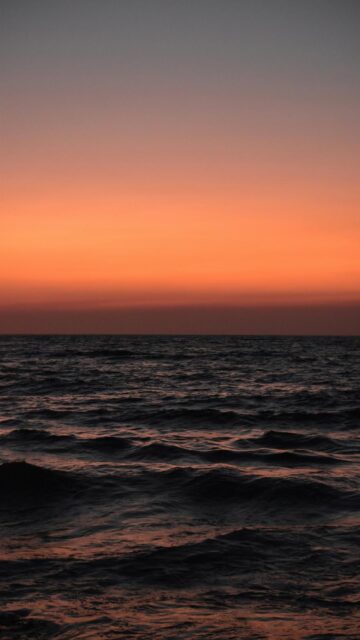 Vibrant Orange Sunset Sky Over Ocean Waves