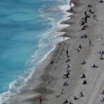 Turquoise Bliss: People Relaxing on Pebble Beach