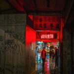 Neon Nights: People Walk Through A Vibrant Alleyway