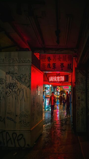 Neon Nights: People Walk Through A Vibrant Alleyway
