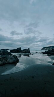Calm Ocean View on Rocky Beach Under Cloudy Sky
