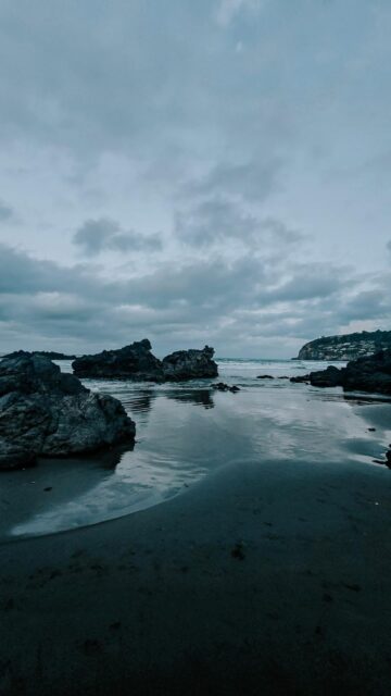 Calm Ocean View on Rocky Beach Under Cloudy Sky