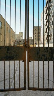 Rusty Metal Gate with Buildings in Background