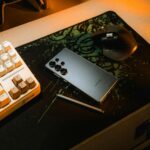 Golden Hour Workspace: Smartphone and Stylus on Desk with Keyboard and Mouse