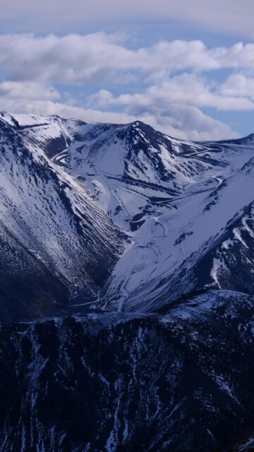 Snowy Peaks Under A Cloudy Blue Sky