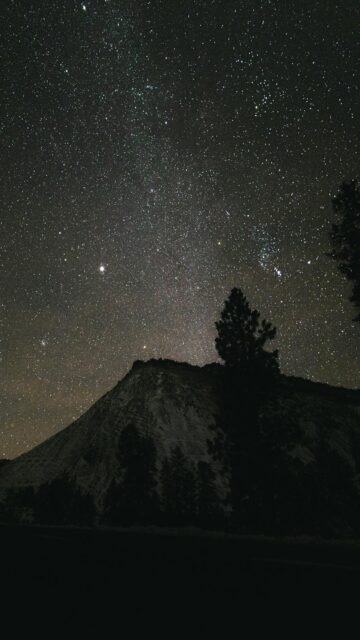 Breathtaking Starry Night Sky Over Mountain Peak Wallpaper