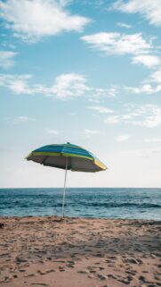 Coastal Relaxation: Striped Beach Umbrella on Sandy Shore