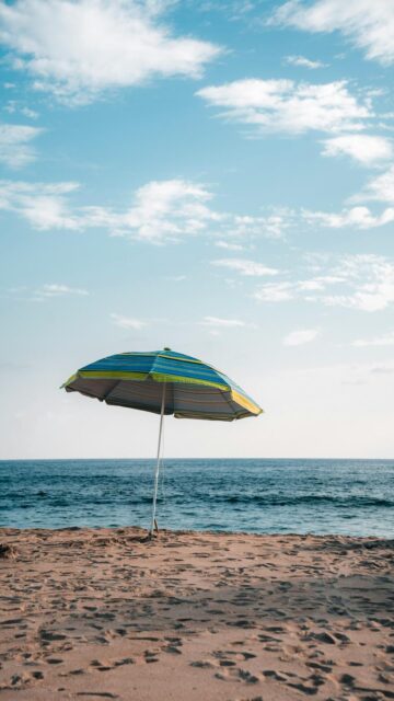 Coastal Relaxation: Striped Beach Umbrella on Sandy Shore
