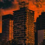 Tall Buildings Silhouetted Against A Fiery Orange Sunset Sky Wallpaper