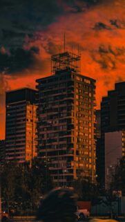 Tall Buildings Silhouetted Against A Fiery Orange Sunset Sky Wallpaper