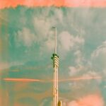 Cloudy Skies Meet Modern Architecture: Tall Communication Tower Wallpaper