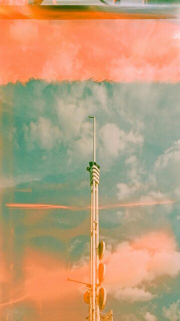 Cloudy Skies Meet Modern Architecture: Tall Communication Tower Wallpaper