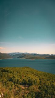 Vast Blue Lake Surrounded by Green Hills and Mountains