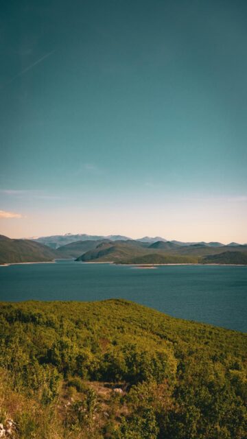 Vast Blue Lake Surrounded by Green Hills and Mountains