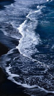 Mobile Wallpaper: Waves Crashing on Dark Sand Beach