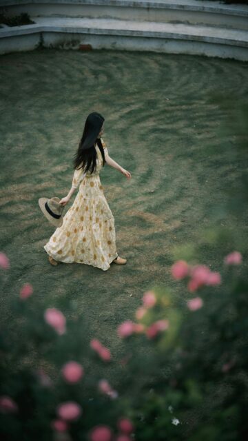Woman In Floral Dress Walks Across Grassy Field