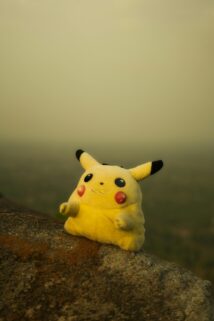 Yellow Pikachu Plush Toy Sitting On A Rock With A Blurred Natural Background – Free 4K HD Download