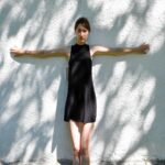 Ethereal Woman in Black Dress Against White Wall