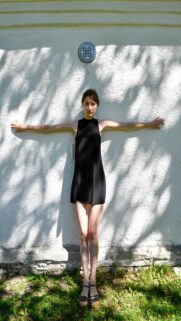 Ethereal Woman in Black Dress Against White Wall