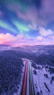Stunning Aurora Borealis Over Snowy Mountain Highway Wallpaper for Mobile
