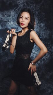 Elegant Asian Woman in Little Black Dress Holding Heels Wallpaper