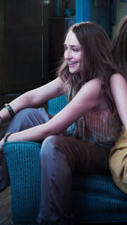 Beautiful Smiling Young Woman Sitting on a Teal Couch High Quality Mobile Wallpaper