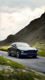 Stunning Aston Martin DBX Driving Through Scenic Mountain Landscape Wallpaper