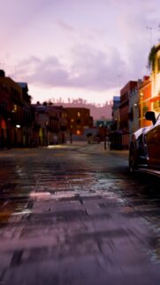 Stunning Sports Car on Cobblestone Street at Dusk Mobile Wallpaper