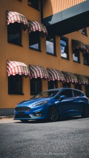 Blue Ford Fiesta ST Parked by Retro Yellow Building Wallpaper
