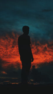 Stunning Silhouette of a Man Against a Dramatic Fiery Sunset Sky Wallpaper