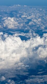 Stunning Aerial View of Airplane Flying Over Massive Fluffy White Clouds Wallpaper